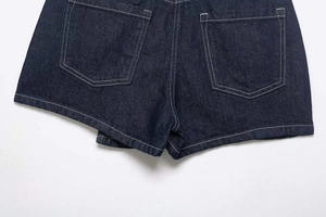 Detail view of dark blue denim shorts back pockets with white contrast stitching accents