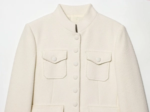 Détail du col montant et des boutons recouverts de tissu sur la veste en tweed