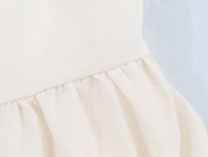 Macro shot of off-white sleeveless dress showing refined stitching and pleated fabric detail