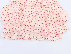 Detail view of red polka dot print on tiered chiffon ruffles for elegant summer halter top