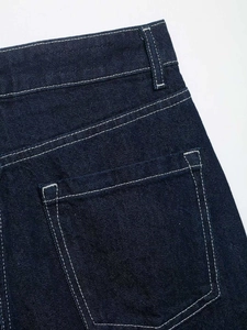 Detailed macro view of dark blue denim fabric with white contrast stitching and texture