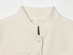 Détail macro du tissu en tweed et des boutons recouverts sur une veste de couleur crème