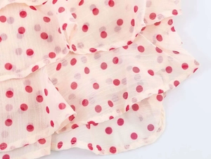 Detail of pink polka dot georgette fabric with tiered ruffle layers and smooth edges
