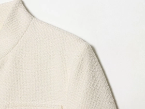 Vue rapprochée de l'épaule et du col montant d'une veste en tweed blanc avec texture