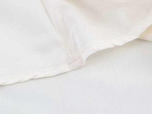 Detailed view of the precise stitching and rolled hem on a white sleeveless dress