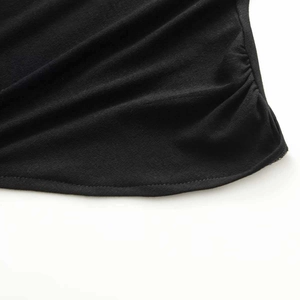 Close-up of minimalist black asymmetrical dress hem with fine stitching and pleat details