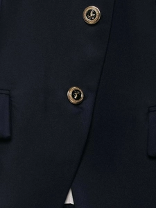 Macro shot of navy blue blazer fabric texture and vintage gold crest metal buttons