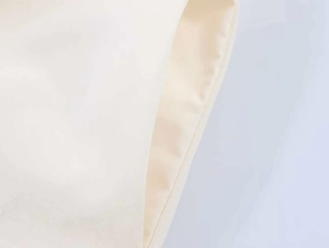Detailed macro view of side pocket stitching on an off-white minimalist sleeveless dress