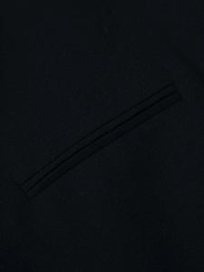 Détail macro de la poche passepoilée et du tissu tissé sur le blazer noir