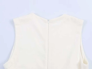 Detail view of the cream sleeveless dress featuring a back invisible zipper and woven texture