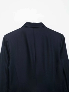 Detail view of the back collar and fine twill texture on a navy blue cropped blazer