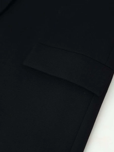 Détail d'un blazer noir montrant le tissu en sergé fin et la poche à rabat