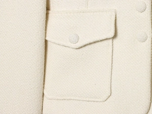 Détail de la veste en coton crème montrant la texture tweed et les boutons recouverts