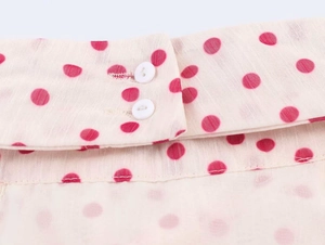 Close-up of pink polka dot georgette fabric with double white buttons and vertical texture