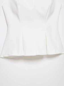Detailed close-up of white sleeveless top showing elegant waist pleats and peplum design