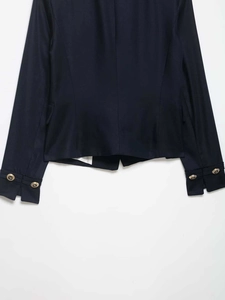 Detailed macro view of navy blazer sleeve featuring embossed gold metal buttons and twill fabric