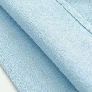 Macro shot of light blue cotton-linen fabric texture with precise stitching detail