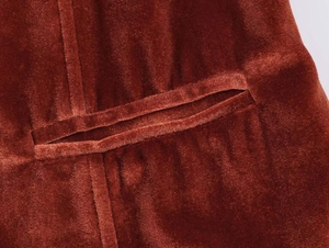 Close-up of rust red velvet jacket fabric showing detailed pocket stitching and texture