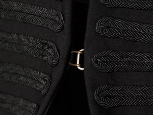 Detailed macro view of black military blazer featuring braided rope and metal hooks