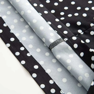 Nahaufnahme der Overlock-Nähte und des weißen Polka-Dot-Musters auf schwarzem Stoff