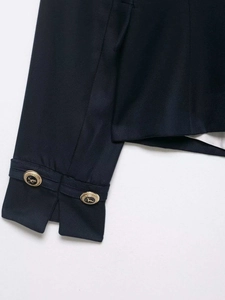 Macro detail of navy blue blazer cuff with decorative gold crest buttons and twill fabric