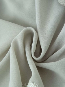 Vista macro del tessuto georgette grigio chiaro con delicato bordo in pizzo bianco