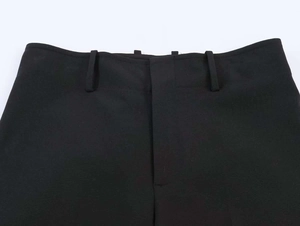 Close-up detail of black suit trousers featuring belt loops and a central zipper fly closure