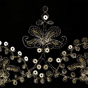 Detail of golden floral embroidery and silver sequins on black velvet vest fabric