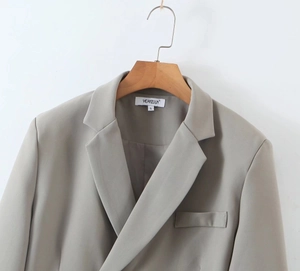 Detailed macro view of the notch lapel and brand label on a grey women's blazer
