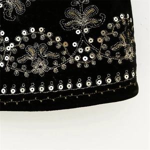 Close-up of velvet fabric with intricate gold embroidery and silver sequins detail