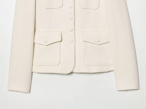 Détail de la veste en tweed ivoire avec tissu texturé et boutons recouverts du même tissu