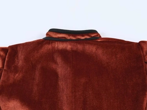 Close-up of rust velvet jacket with stand-up collar and black ribbed trim details