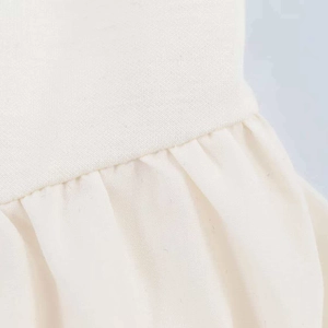 Minimalist off-white sleeveless dress featuring knitted and woven patchwork details