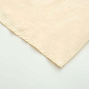 Detailed macro shot of the cream beige cotton linen fabric with ruffled sleeve edges