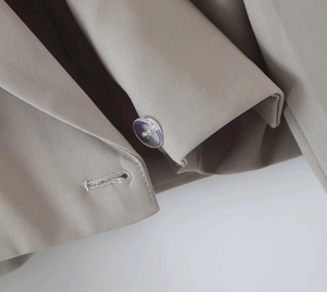 Detailed macro view of a clear resin button and stitching on grey twill suit jacket