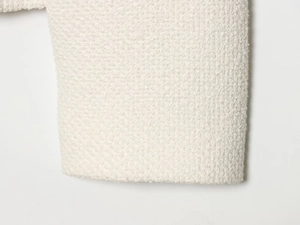 Détail du tissu tweed bouclé blanc montrant la texture tissée et la qualité de la fibre