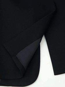 Détail d'un blazer noir montrant la texture du sergé et la doublure intérieure lisse