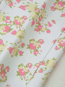 Macro detail of floral print fabric with pink and yellow flowers on white twill material