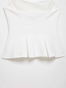 Detail view of white halter top featuring a pleated hem and premium structured fabric