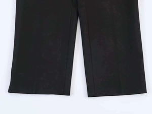 Detailed view of black trousers showing premium woven fabric texture and sharp ironed pleat