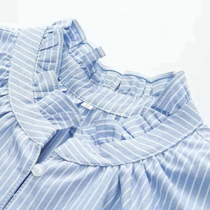 Close-up of ruffled collar detail and white button on a blue striped cotton shirt