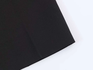 Detail shot of the black blazer fabric featuring irregular hem and smooth texture finish