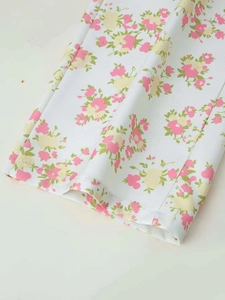 Detail of floral printed wide leg trousers in white woven fabric with pink blossoms
