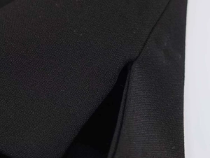 Detail showing the slit hem tailoring and twill fabric texture of the black suit