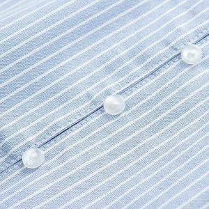Detailed macro view of the blue striped fabric and white buttons on a summer shirt