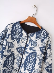 Detail of blue floral print on quilted jacket with round neck and single-breasted buttons
