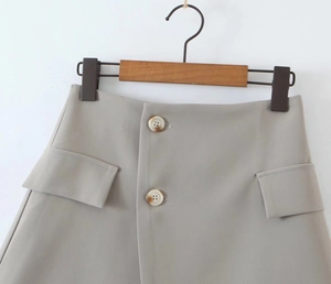 Close-up of grey office skirt featuring marble buttons and flap pocket details
