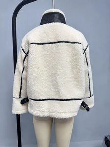 Dettaglio della giacca bianca in shearling con profili in pelle nera e fibbie