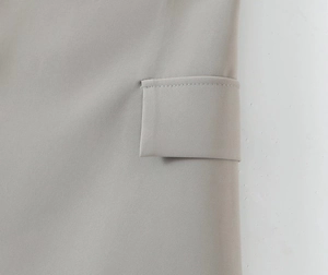 Detail shot of a light gray blazer pocket with fine twill texture and neat stitching