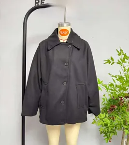 Detail of a black short wool coat featuring a large lapel and classic button closure